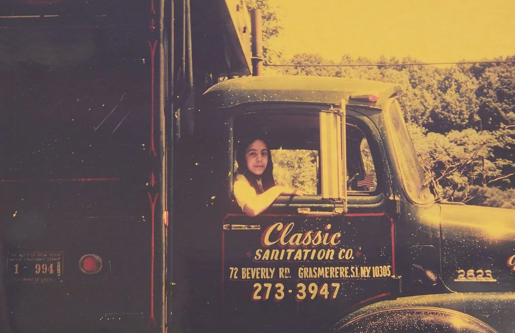 A girl in the cab of an early Classic Sanitation Co. truck
